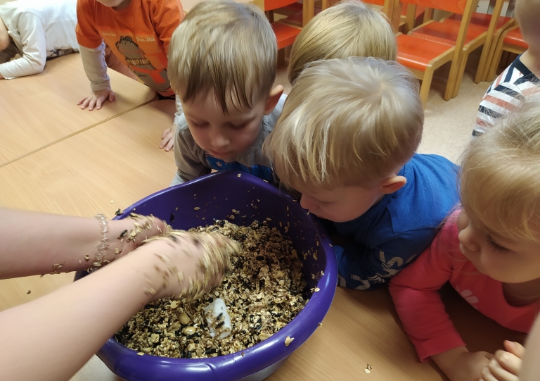 Dzieci przygotowują zawieszki z ziaren dla ptaków